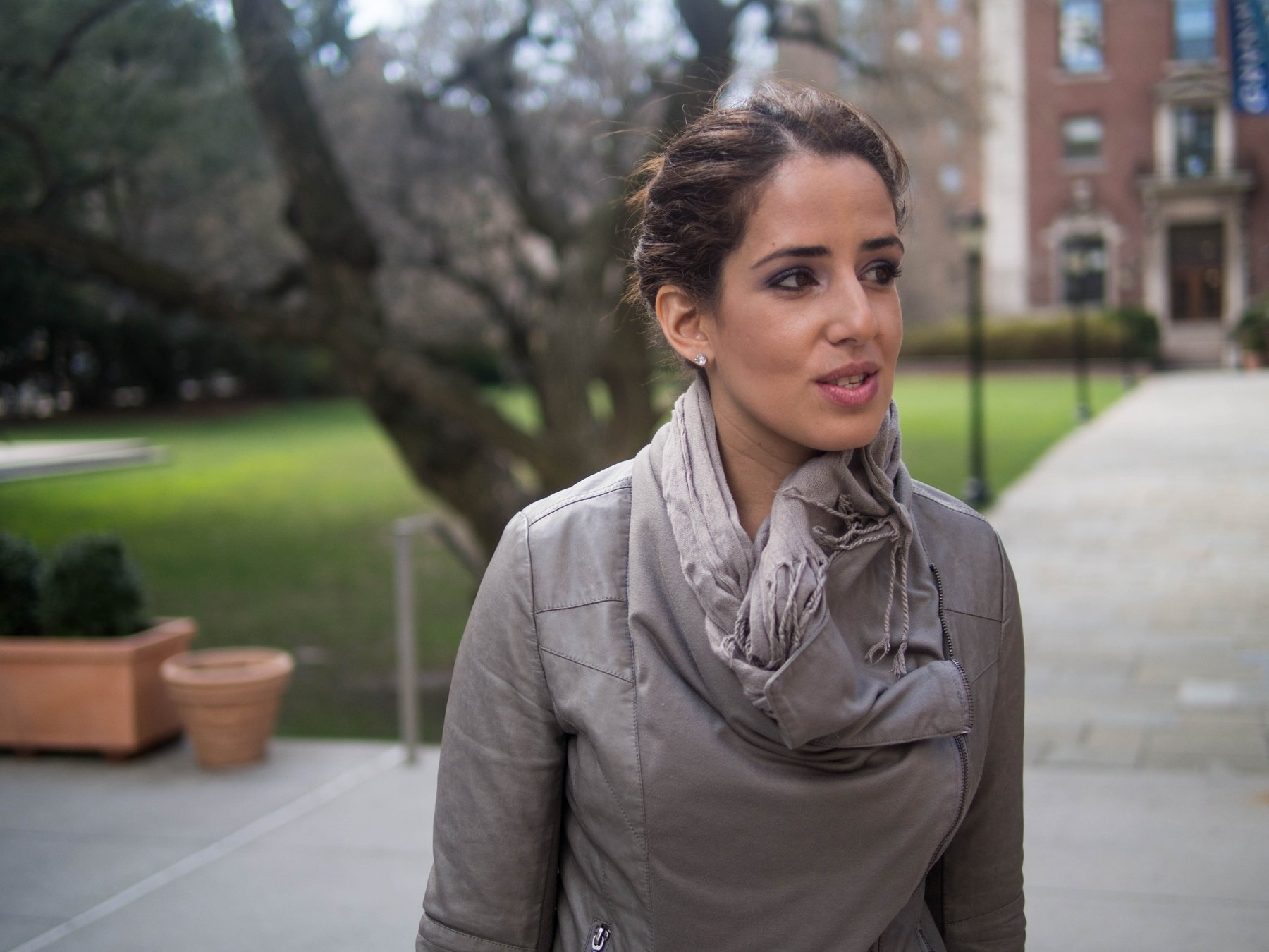 A woman in a scarf sitting on a park bench.