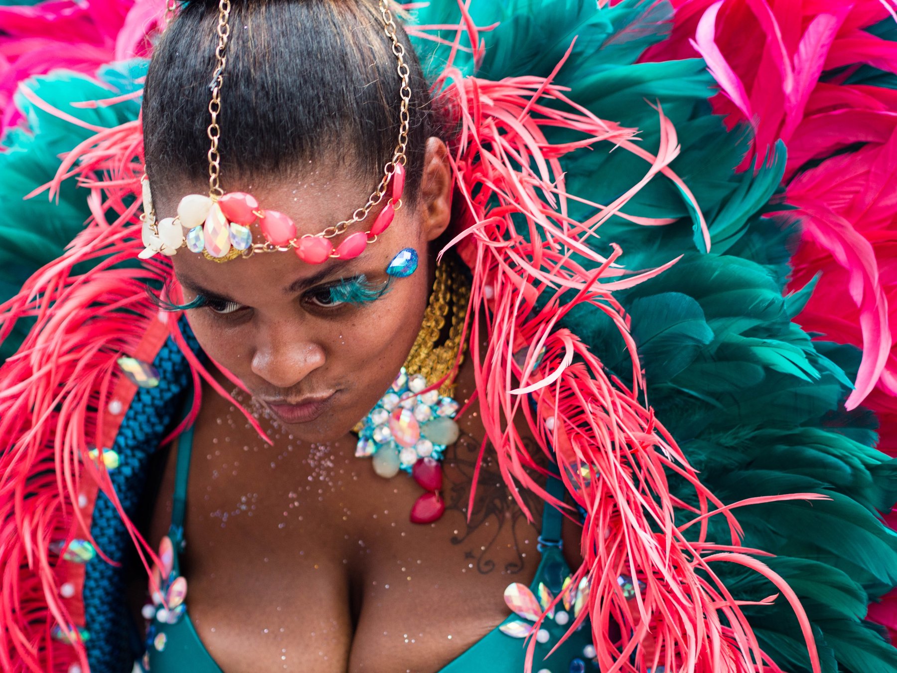 A close view of a dancer surrounded by vivid pink and turquoise feathers.